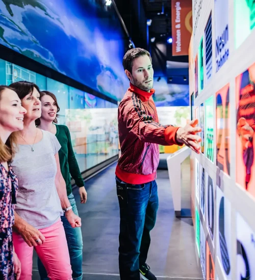Besucher betrachten Bilder der Ausstellung, ein Mann zeigt auf ein Bild.
