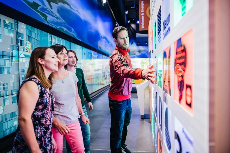 Besucher betrachten Bilder der Ausstellung, ein Mann zeigt auf ein Bild.